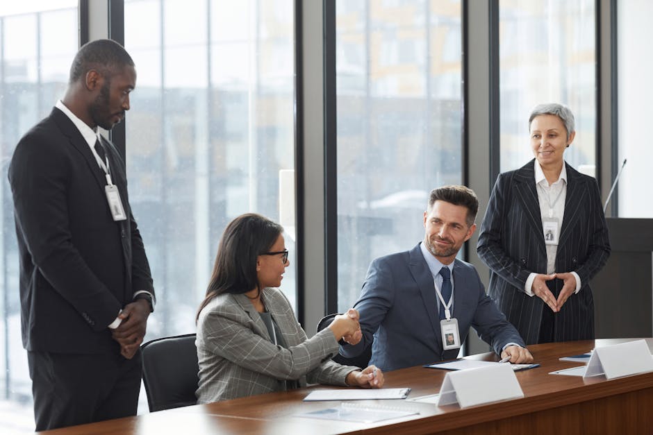 A diverse group of professionals shaking hands during a business meeting in a modern office.